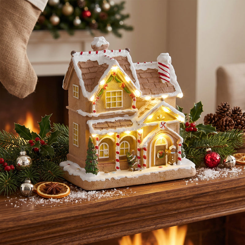 Gingerbread house on a mantel with pine cones and Christmas baubles