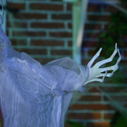 Close-up of the witch's pale bony hand against a brick wall