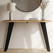 Live edge acacia wood console table with angular black iron legs styled in a hallway
