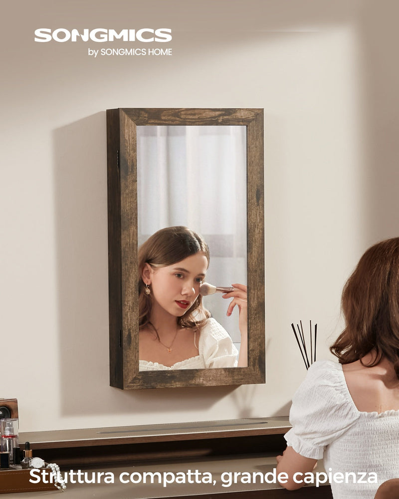Woman applying make-up in the mirror of the rustic brown jewellery cabinet mounted on a bedroom wall