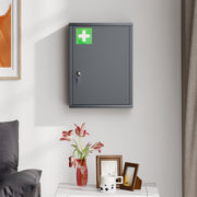 Closed smoke grey medicine cabinet with a green first aid cross mounted on a wall above a table with photo frames and a vase
