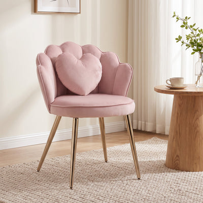 Pink accent chair styled in a bedroom beside a round wooden side table