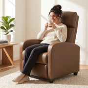 Woman sitting upright in the dark brown recliner armchair drinking coffee