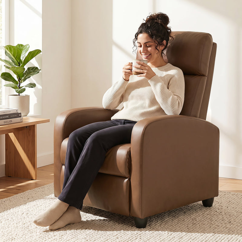 Woman sitting upright in the dark brown recliner armchair drinking coffee