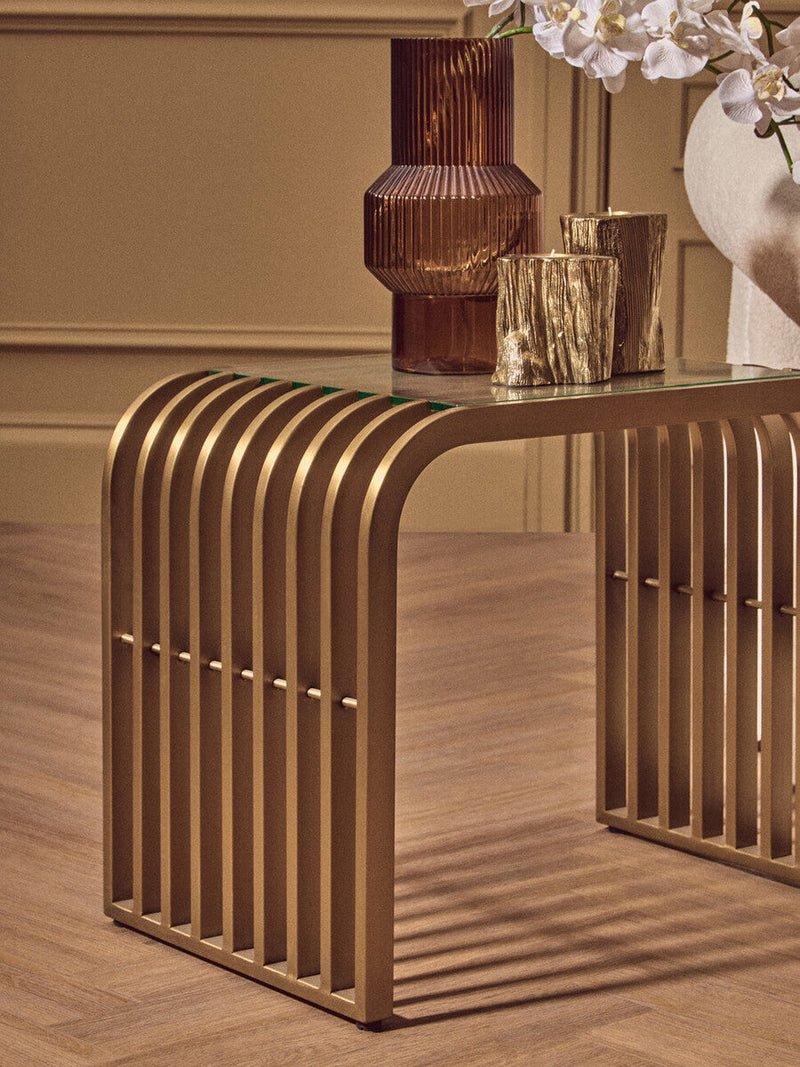 Gold slatted end table in a room setting beside an armchair