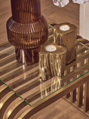 Matte gold end table styled with candles and greenery in a living room