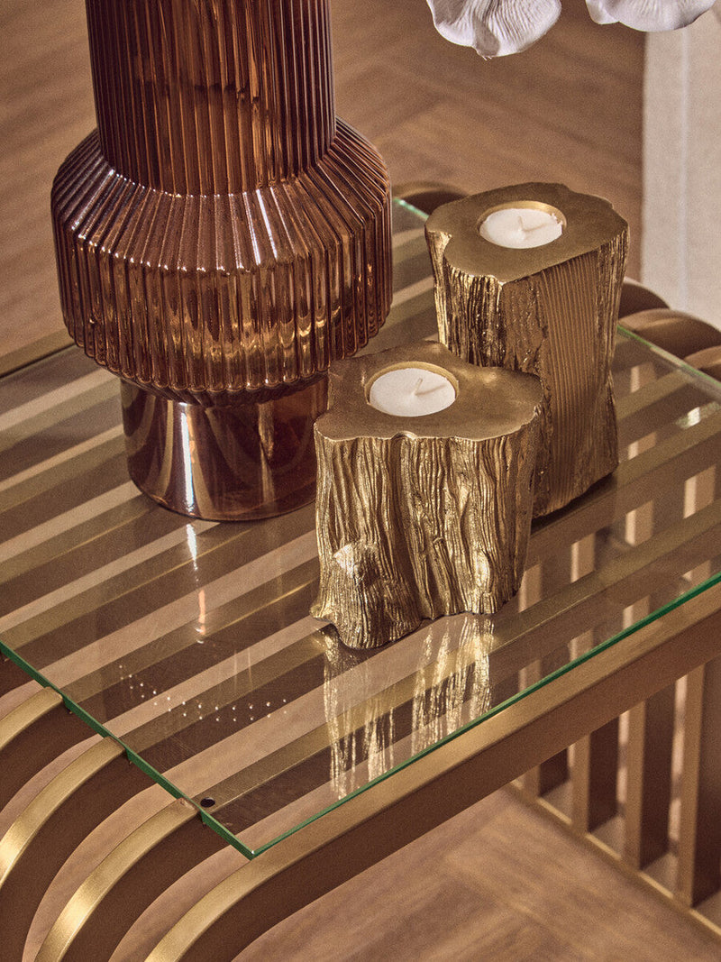 Matte gold end table styled with candles and greenery in a living room