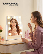 Woman applying lipstick at a dressing table with the compact lit vanity mirror
