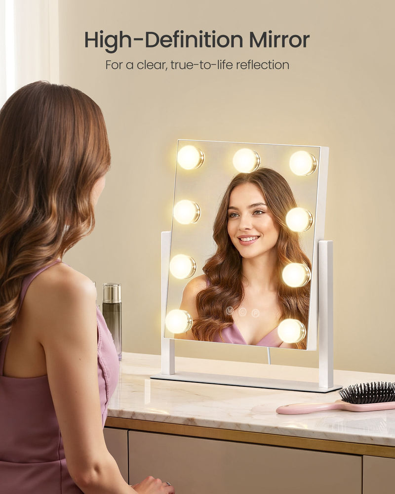 Woman smiling into the compact lit vanity mirror on a dressing table