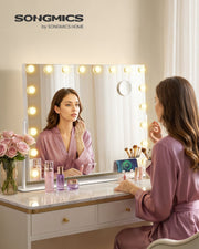 Woman doing her makeup at a dressing table with the lit vanity mirror