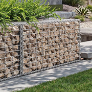 Stone-filled gabion wall edging a raised garden border beside a lawn