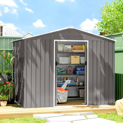 Light grey metal shed on garden decking with sliding doors open showing shelves of storage boxes
