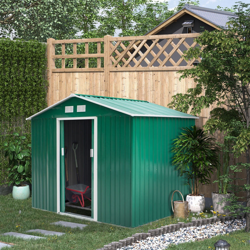 Green shed against a wooden fence with the sliding door open and a wheelbarrow inside