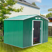 Green metal garden shed beside a house with the sliding doors open and a wheelbarrow stored inside