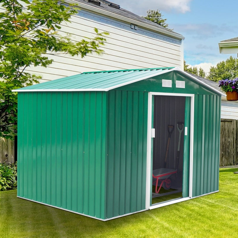Green metal garden shed beside a house with the sliding doors open and a wheelbarrow stored inside