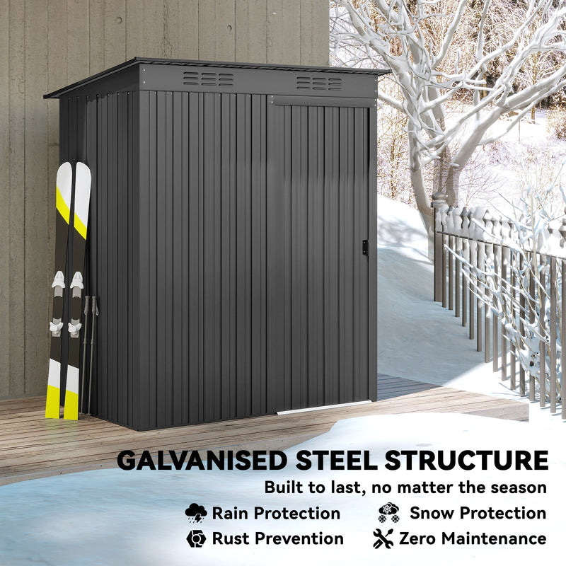 Dark grey metal garden shed standing in snow with skis leaning against the side