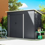 Dark grey pent roof metal shed closed, standing against a house wall in a garden