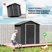 Dark grey metal shed placed against a fence to reduce wind exposure in a garden