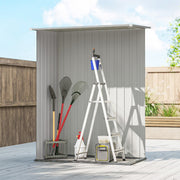 Grey metal shed on a patio with spades, a ladder and hand tools standing in front of it