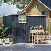 Long side of the dark grey shed with its window, beside a cabin and planters