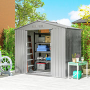 Silver metal shed on a patio with the sliding doors open showing stored garden kit