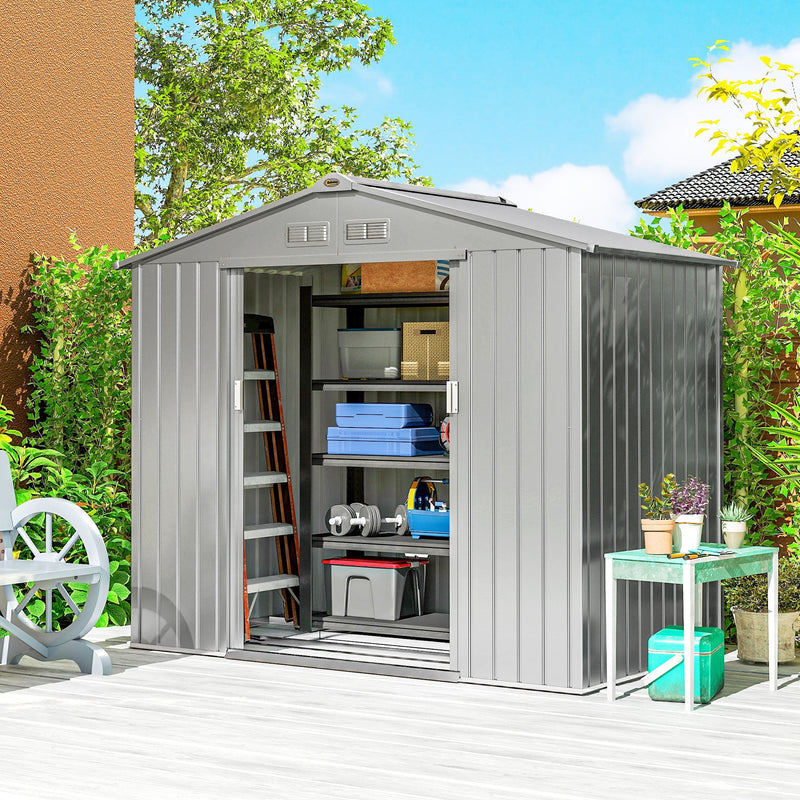 Silver metal shed on a patio with the sliding doors open showing stored garden kit