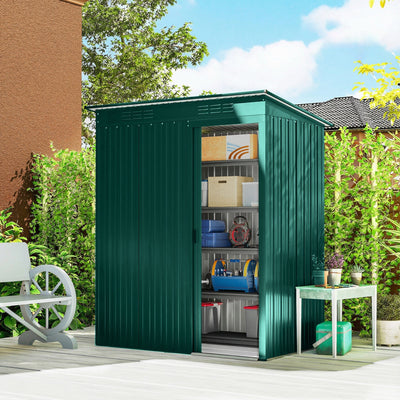 Green metal shed on a patio with the sliding door open showing stored tools
