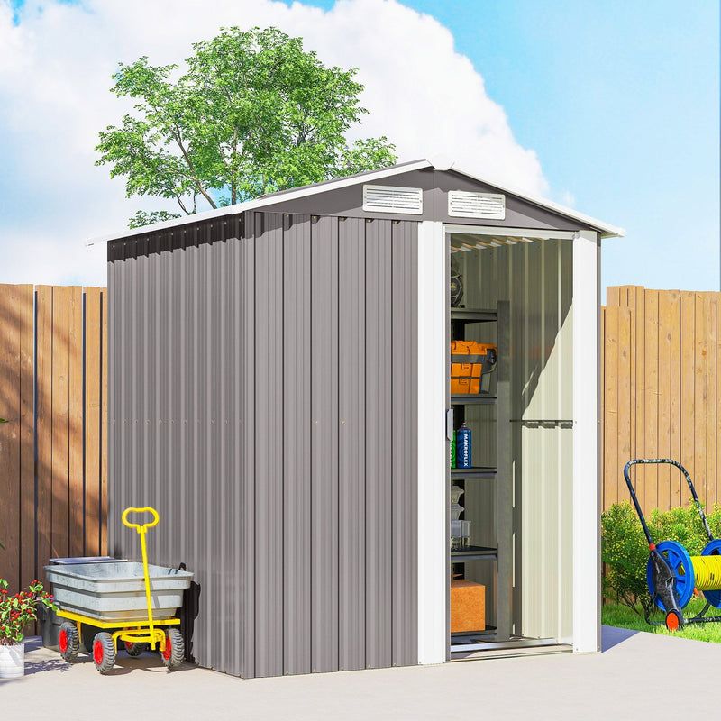 Angled view of the grey shed with the door open, a hose reel and a garden trolley alongside