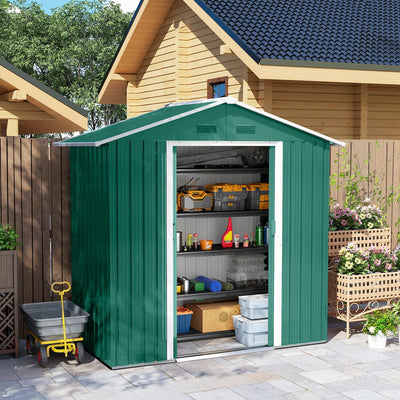 Green metal shed beside a log cabin with the sliding doors open and tools stored inside