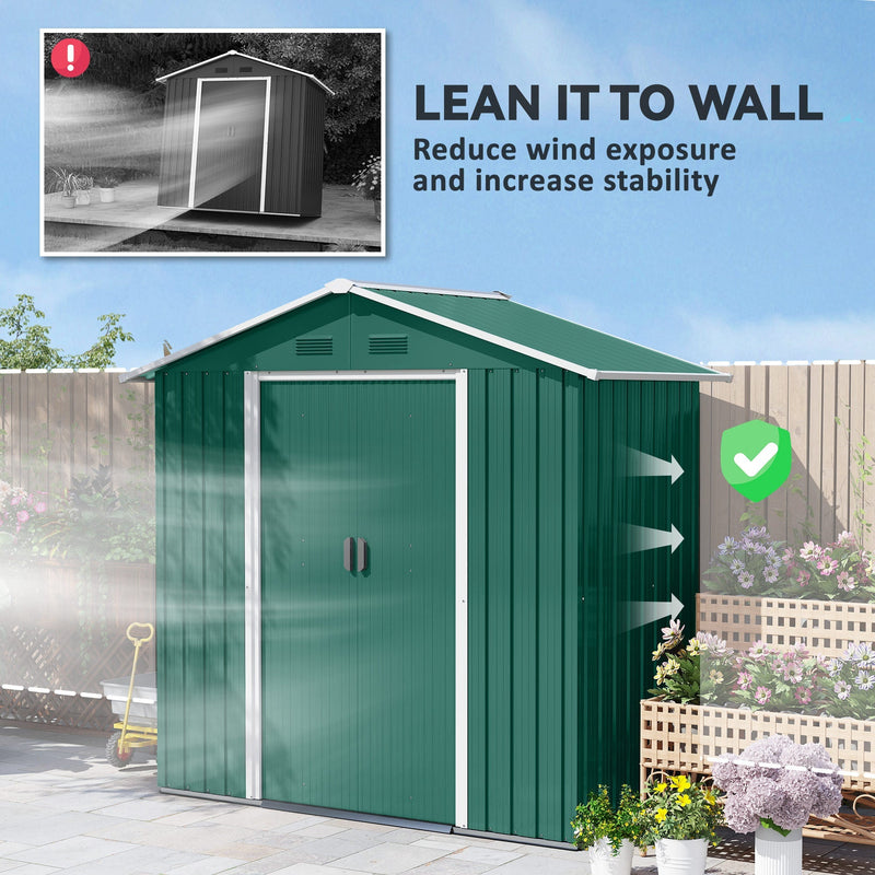 Green metal shed placed against a fence panel to cut wind exposure