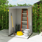 Inside the grey shed holding a step ladder, spade, coiled hose and metal bucket