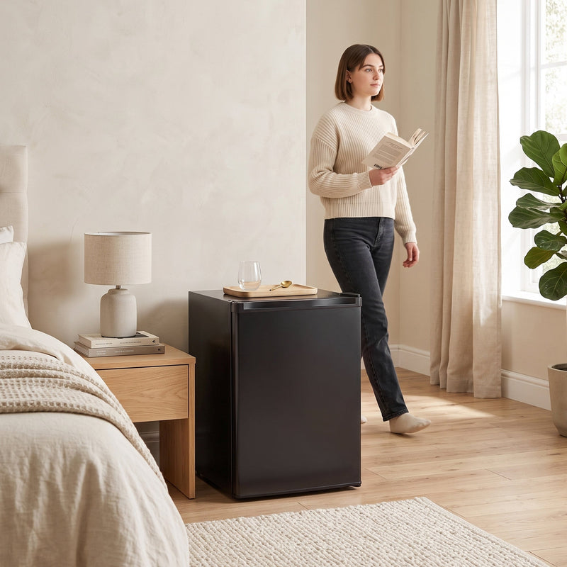 Black mini fridge beside a bed in a bedroom