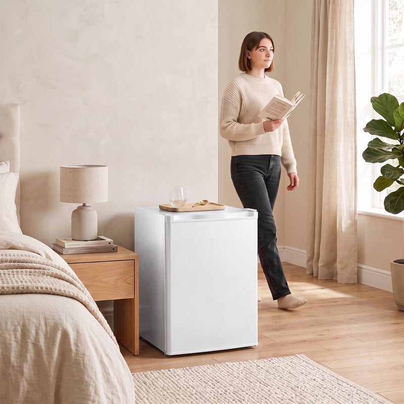 White mini fridge beside a bed in a bedroom