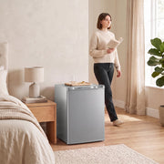 Grey mini fridge beside a bed in a bedroom