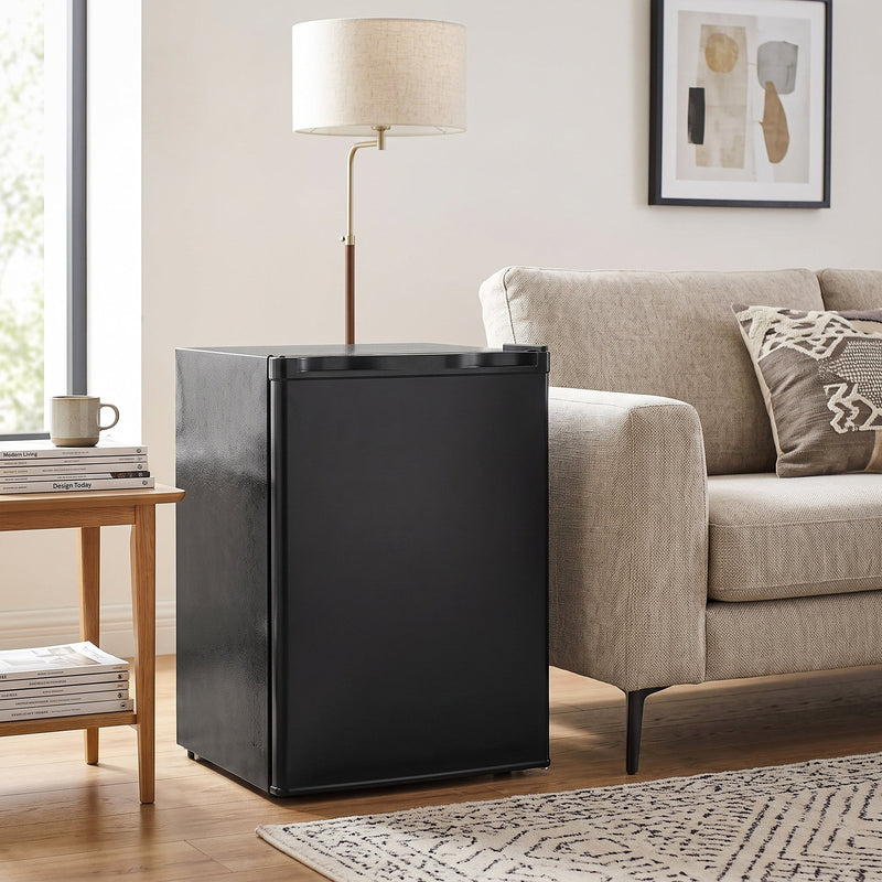 Black mini fridge next to a sofa and side table in a living room