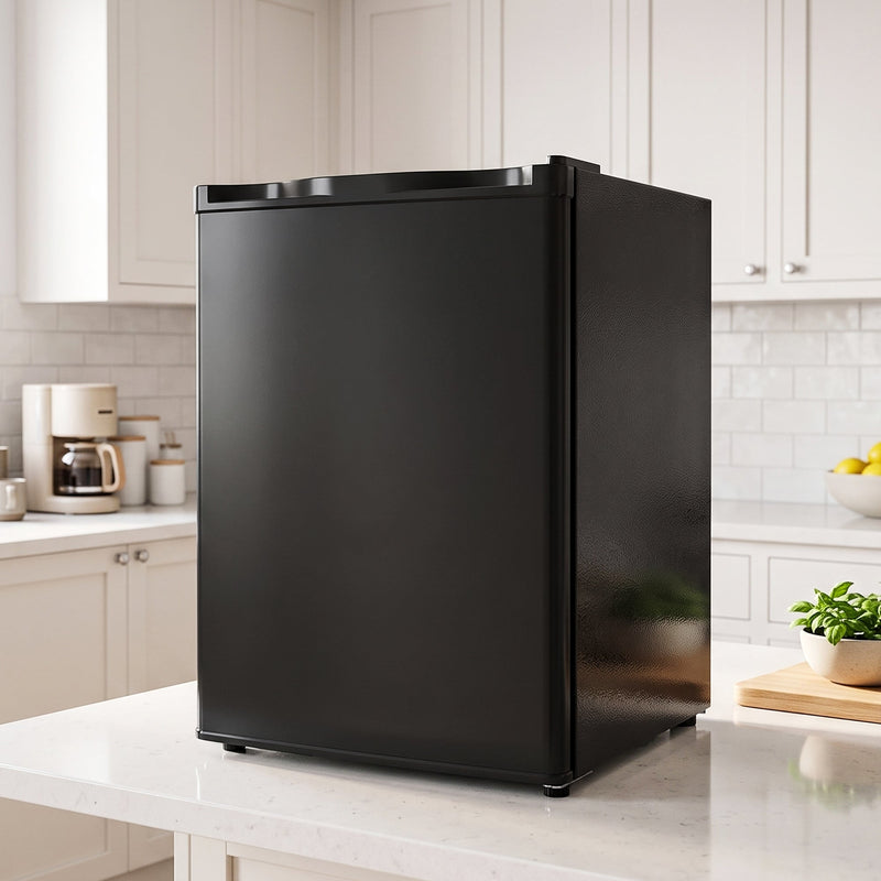 Black mini fridge on a kitchen worktop beside white cabinets