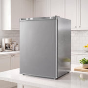 Grey mini fridge on a kitchen worktop beside white cabinets