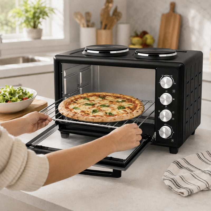 Hands lifting a cooked margherita pizza on the wire rack out of the open 46L mini oven