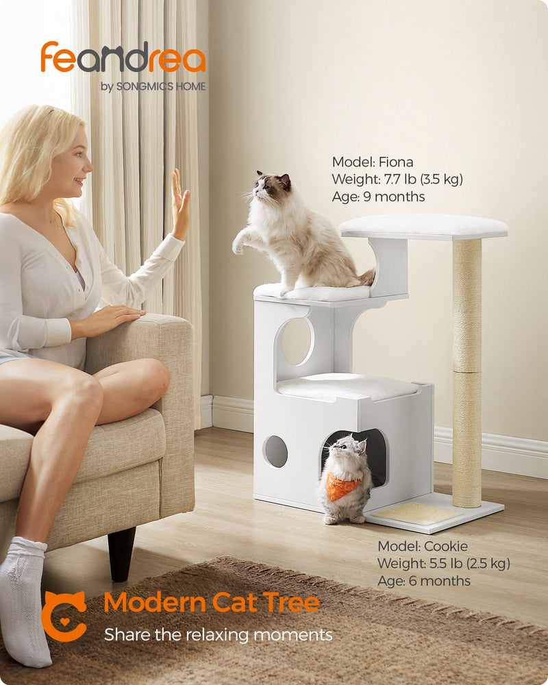 Cloud white cat tree beside an armchair with a cat on the top perch and another in the cave