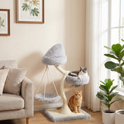 Grey cat lying on the side bed of the cat tree with a ginger cat sitting beside the base in a living room