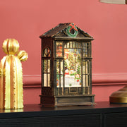 Snow globe lantern on a black table beside a gold cactus ornament against a red wall