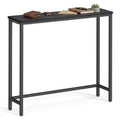 Black narrow steel console table with black wood-grain top, wallet, keys, notebooks and a small plant on top