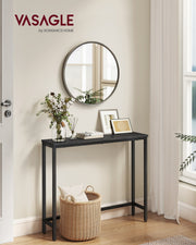 Black narrow console table in a hallway beneath a round mirror with a woven basket underneath