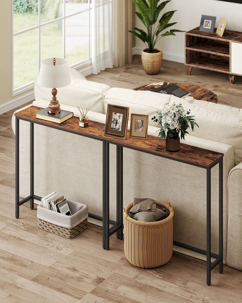 Two rustic brown narrow console tables placed end to end behind a sofa in a living room