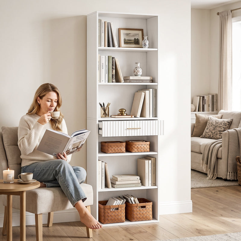White bookcase in a living room beside a woman reading with a coffee