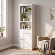 White bookcase with 3 open shelves and 3 drawers styled with books and plants next to an armchair