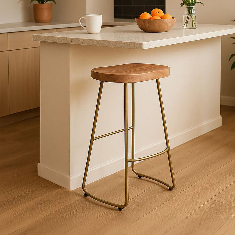 Natural acacia wood bar stool with antique brass finish frame at a kitchen counter