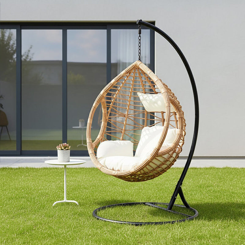 Natural rattan effect hanging chair with cream cushion styled in a living room