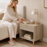 Woman placing a book on the natural wood bedside table next to her bed