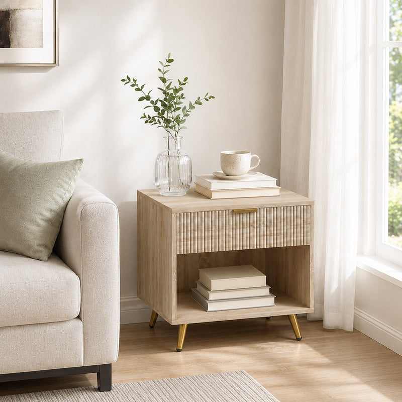 Natural wood bedside table styled in a living room beside a sofa with a plant